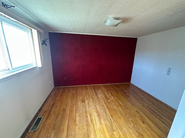 unfurnished room featuring a textured ceiling and light wood-type flooring