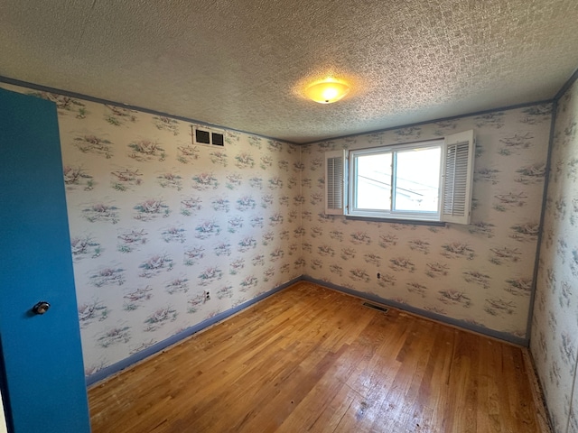 empty room featuring wood-type flooring and a textured ceiling