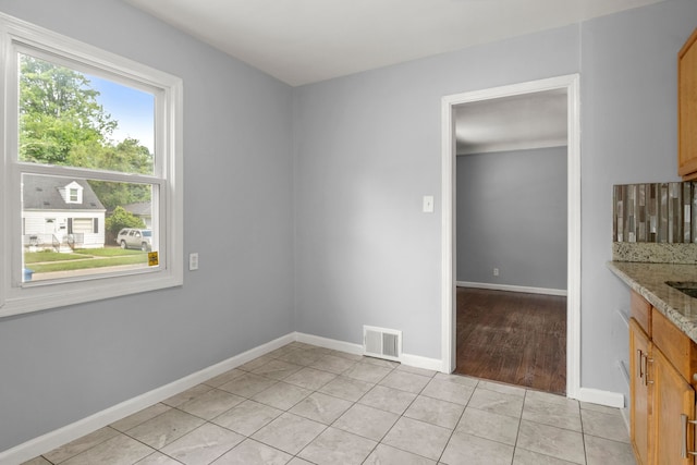 interior space featuring light stone countertops, light tile patterned floors, and decorative backsplash