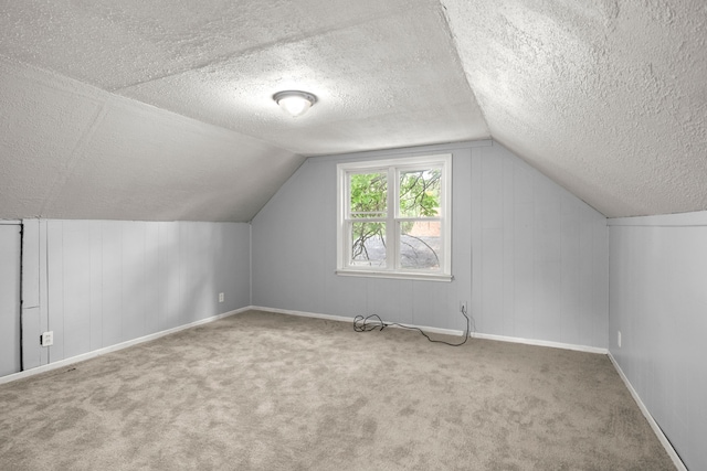 additional living space with vaulted ceiling, carpet floors, and a textured ceiling