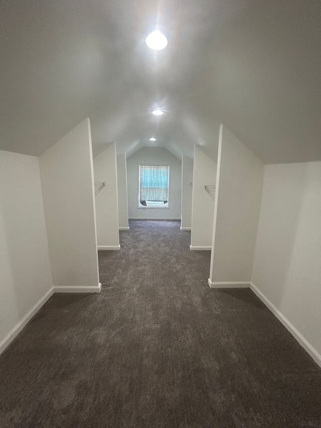 additional living space with dark colored carpet and vaulted ceiling