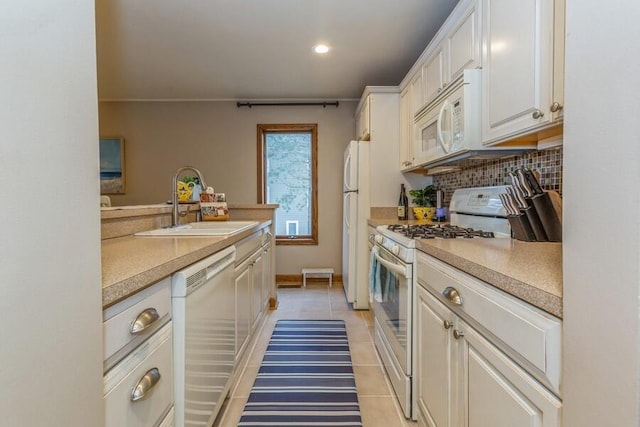 kitchen with sink, white appliances, backsplash, white cabinets, and light tile patterned flooring