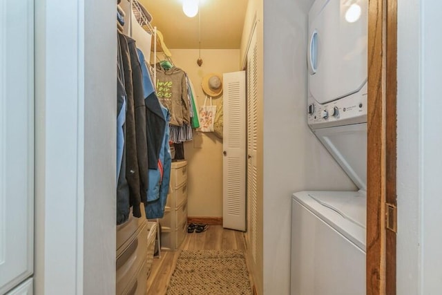 laundry room featuring stacked washer and dryer and light wood-type flooring