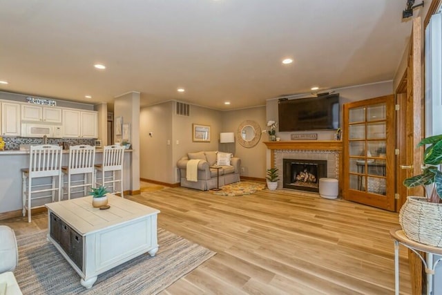 living room featuring a tile fireplace and light hardwood / wood-style flooring