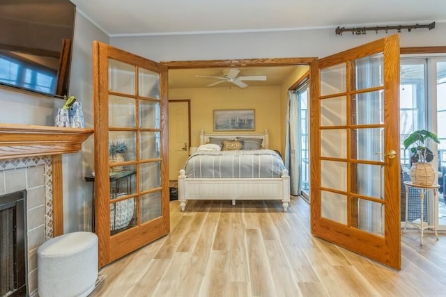 bedroom with light hardwood / wood-style floors, a fireplace, and french doors