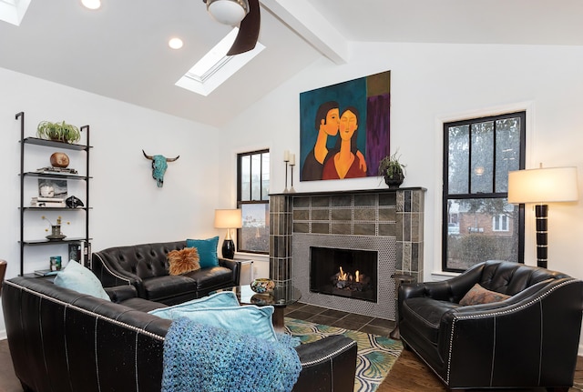 living room featuring a tile fireplace, vaulted ceiling with skylight, and dark hardwood / wood-style flooring