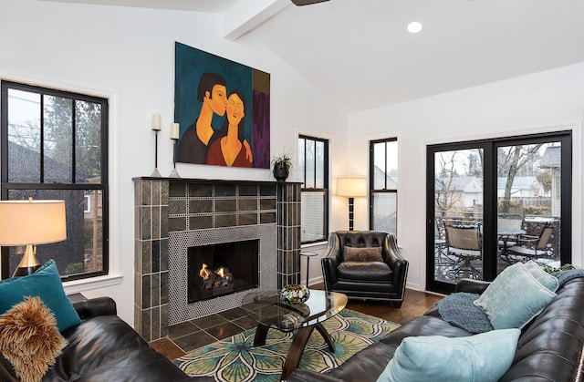 living room with dark wood-type flooring, a healthy amount of sunlight, lofted ceiling with beams, and a tile fireplace