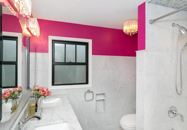 full bathroom featuring vanity, tiled shower / bath, tile walls, and toilet