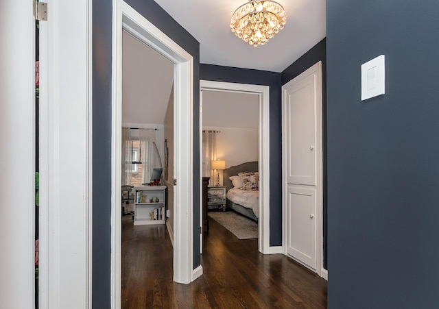 hallway with dark wood-type flooring and a chandelier