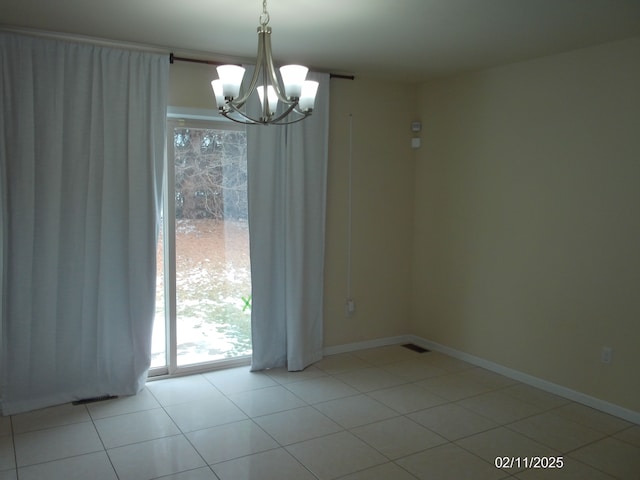 tiled spare room with a chandelier