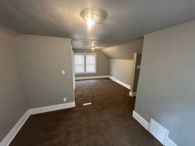 bonus room with dark carpet and vaulted ceiling