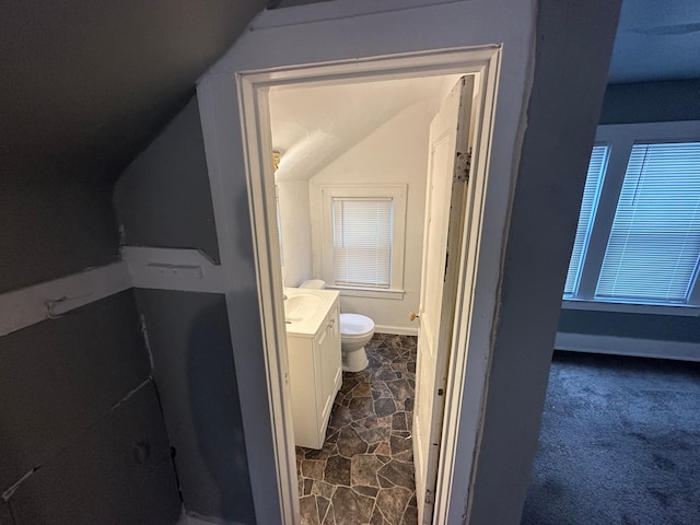 bathroom with vanity, lofted ceiling, and toilet