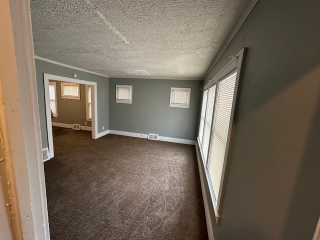 unfurnished bedroom featuring ornamental molding, dark carpet, a textured ceiling, and a closet