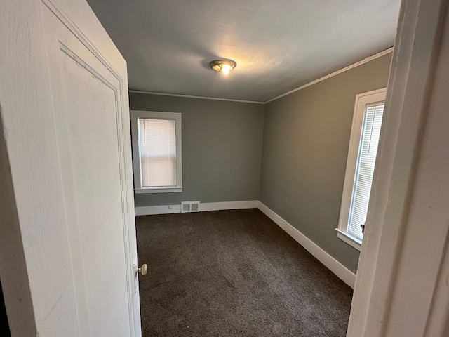 unfurnished room featuring ornamental molding and dark colored carpet