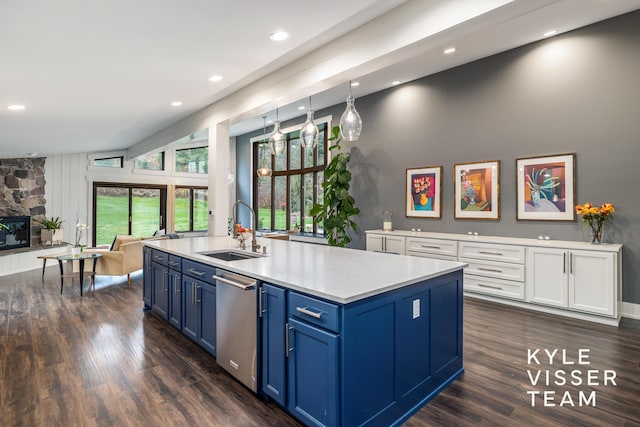 kitchen with sink, dishwasher, white cabinetry, blue cabinets, and a stone fireplace