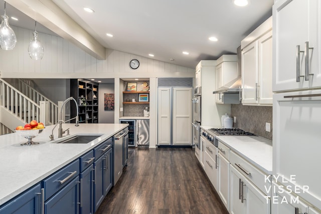 kitchen with blue cabinetry, sink, vaulted ceiling, hanging light fixtures, and white cabinets