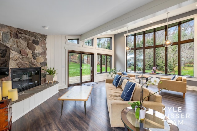 living room with a stone fireplace and dark hardwood / wood-style floors