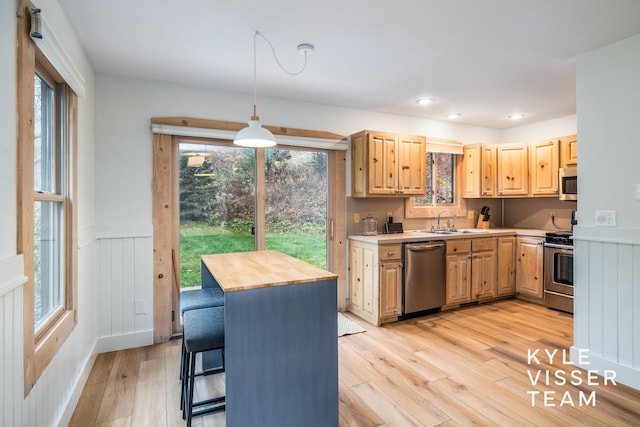 kitchen featuring wooden counters, light brown cabinets, appliances with stainless steel finishes, pendant lighting, and light hardwood / wood-style floors