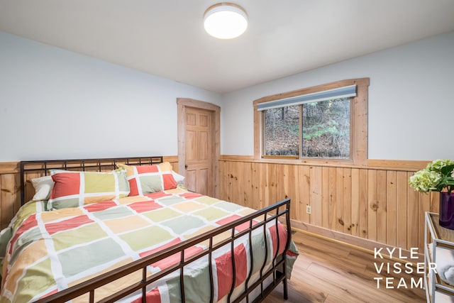 bedroom featuring wood-type flooring and wood walls