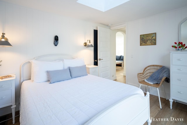 bedroom with a skylight and hardwood / wood-style floors