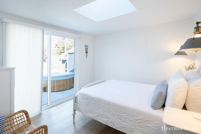 bedroom featuring hardwood / wood-style flooring, a skylight, and access to outside