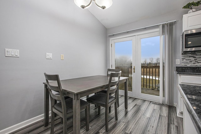 dining space featuring french doors, wood-type flooring, and vaulted ceiling