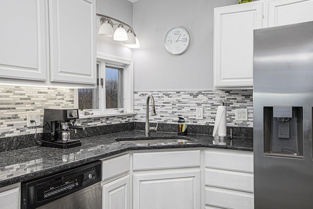 kitchen with white cabinetry, stainless steel appliances, sink, and dark stone counters