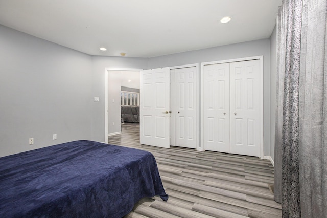 bedroom with multiple closets and wood-type flooring