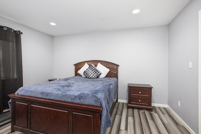 bedroom featuring a baseboard heating unit and dark hardwood / wood-style flooring