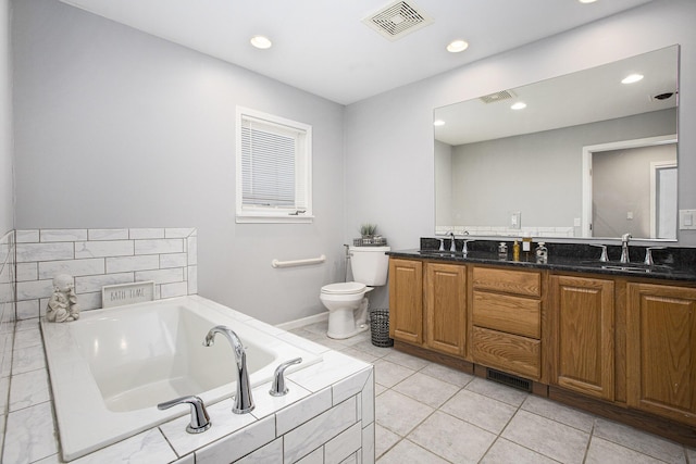 bathroom featuring tiled tub, vanity, tile patterned flooring, and toilet