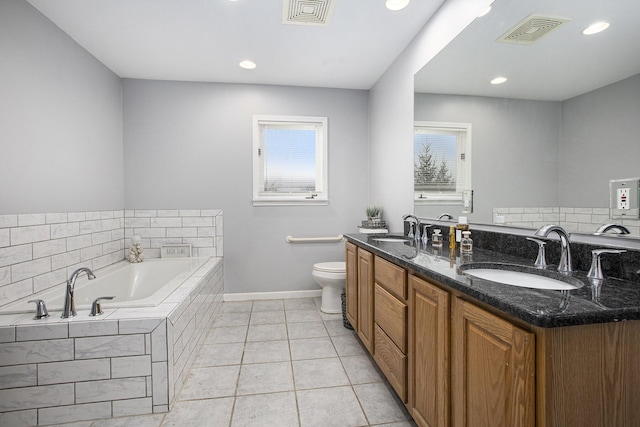 bathroom with tile patterned flooring, vanity, tiled bath, and toilet