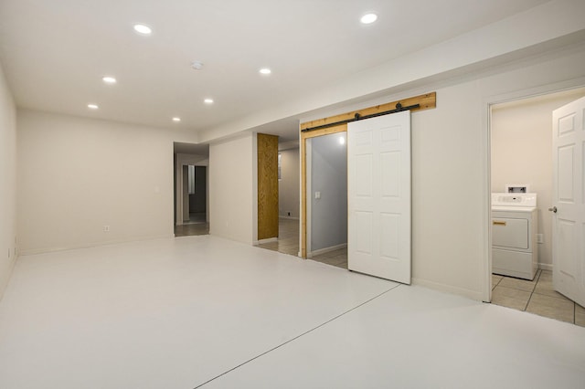 unfurnished bedroom featuring a barn door, washer / dryer, and connected bathroom