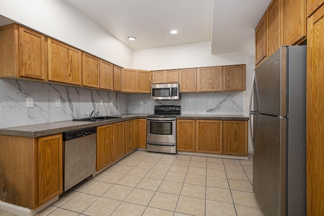 kitchen with appliances with stainless steel finishes, sink, light tile patterned floors, and decorative backsplash