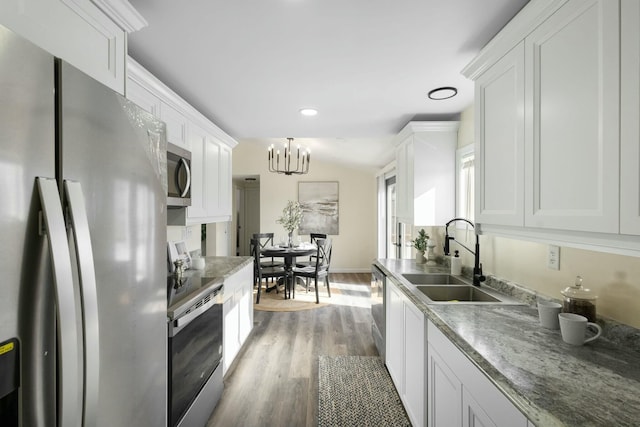 kitchen with white cabinetry, lofted ceiling, sink, stainless steel appliances, and dark wood-type flooring