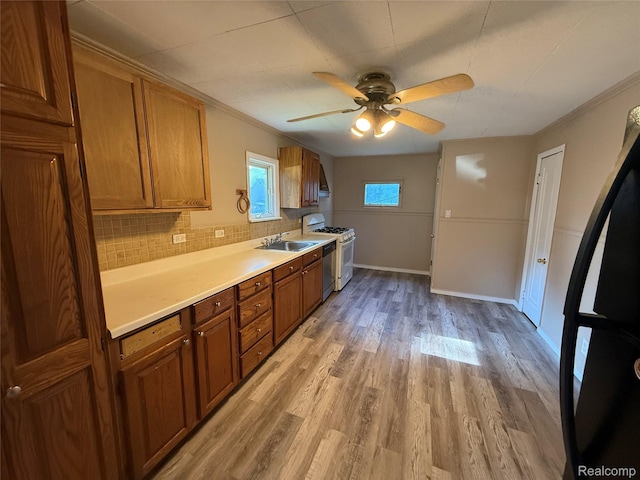 2372 E Boatfield Ave, Burton, MI 48529 - kitchen featuring gas range gas stove, brown cabinetry, light wood-type flooring, a ceiling fan, and light countertops