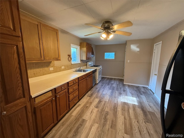 2372 E Boatfield Ave, Burton, MI 48529 - kitchen featuring white gas stove, brown cabinets, light wood finished floors, ceiling fan, and light countertops