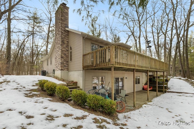 snow covered property featuring a wooden deck and central AC unit