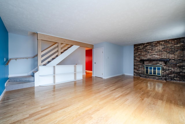 unfurnished living room with wood-type flooring, a textured ceiling, and a fireplace