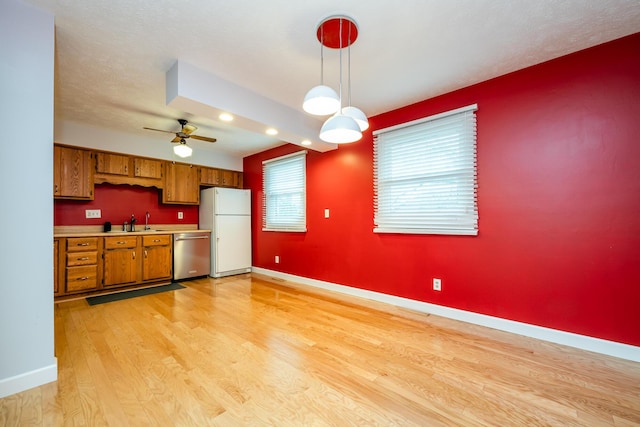 kitchen featuring light wood-type flooring, white refrigerator, stainless steel dishwasher, pendant lighting, and ceiling fan