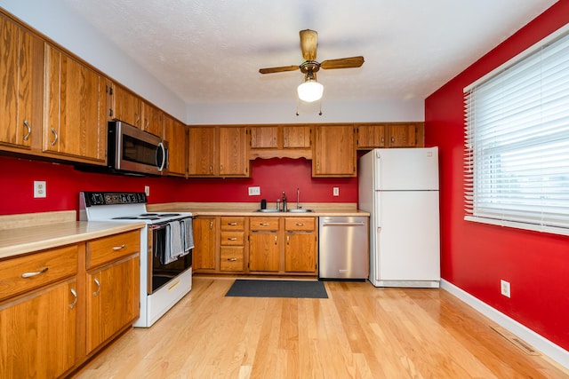 kitchen featuring sink, light hardwood / wood-style flooring, ceiling fan, and appliances with stainless steel finishes