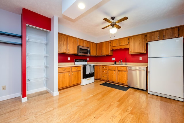 kitchen with ceiling fan, appliances with stainless steel finishes, sink, and light wood-type flooring