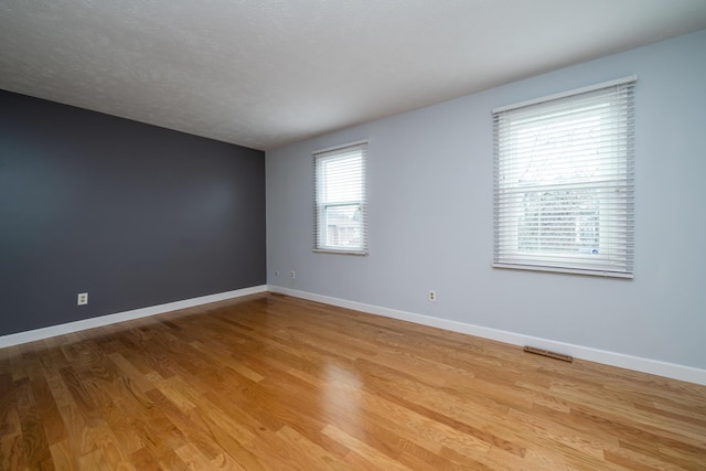 spare room with light hardwood / wood-style floors and a textured ceiling