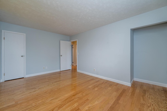 empty room with light hardwood / wood-style floors and a textured ceiling