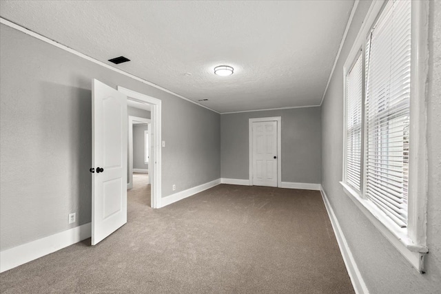 carpeted empty room with ornamental molding and a textured ceiling