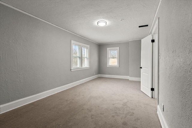 spare room with light colored carpet and a textured ceiling