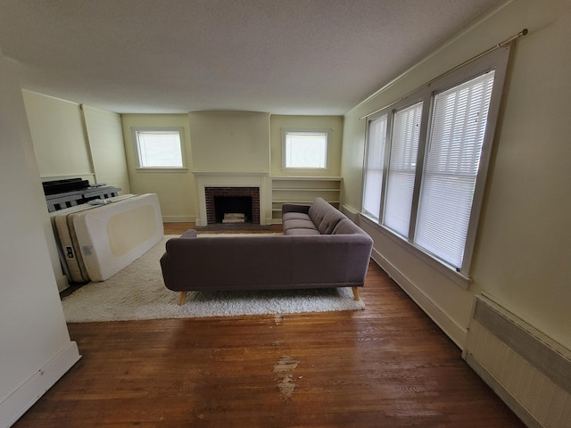 living room featuring a fireplace, radiator heating unit, dark hardwood / wood-style floors, and a textured ceiling