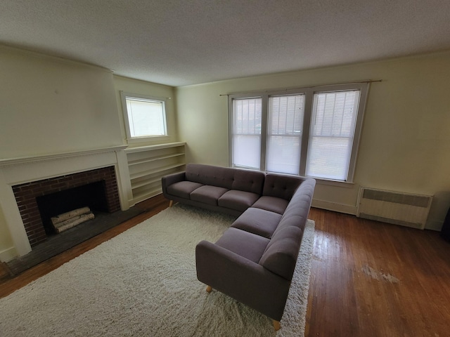 living room featuring dark hardwood / wood-style floors, a fireplace, radiator, and a textured ceiling