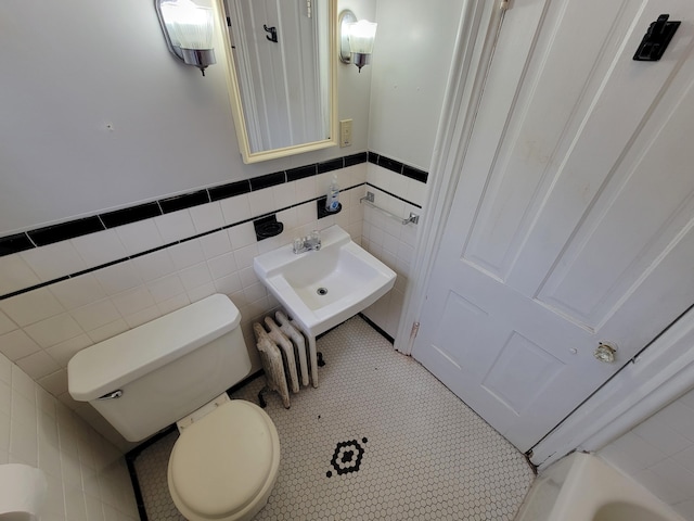 bathroom featuring sink, tile walls, and toilet