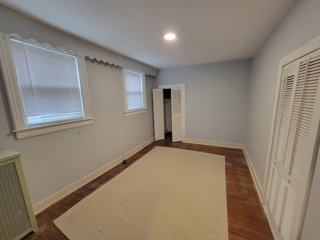 unfurnished bedroom featuring dark hardwood / wood-style floors and radiator