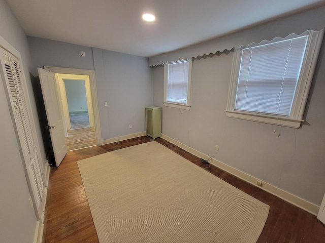 unfurnished bedroom with dark hardwood / wood-style floors and radiator heating unit